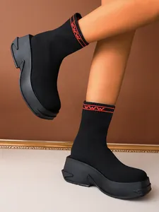 Detailed view of women's black knit platform sock boots featuring red ribbed cuffs