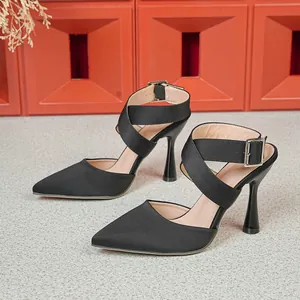 Nahaufnahme schwarzer Stöckelschuhe mit spitzer Kappe, eleganten Kreuzgurten und Schnallen