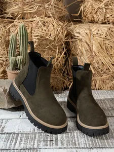 Women's dark olive green suede Chelsea boots featuring chunky black lug soles and tan stitching