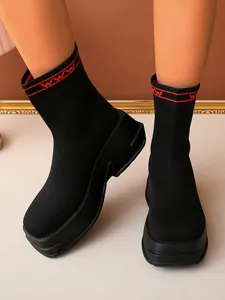 Black fly-knit ankle sock boots featuring a chunky platform sole and red cuff accents
