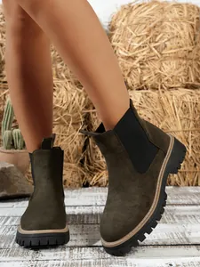 Close-up of olive green suede Chelsea boots with chunky lug soles