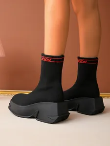 Side view of stylish black knitted platform sock boots with red pattern detail on cuff