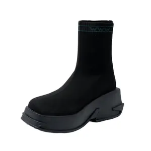 Detailed side view of a black knitted platform sock boot with green cuff trim