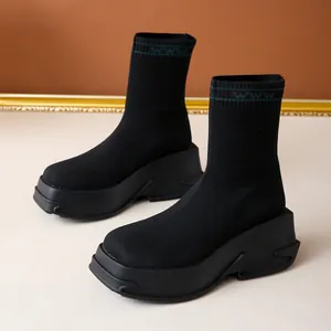 Close-up view of black knit sock boots with thick platform sole and green cuff detail