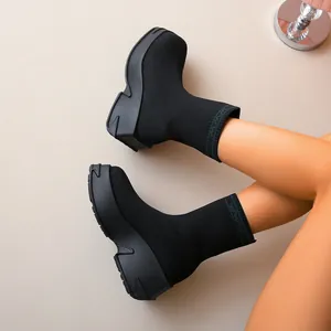 Detailed view of breathable black fly-knit sock boots with chunky platform soles on a model.