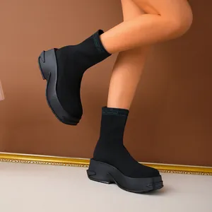Stylish black breathable fly-knit sock boots with a chunky platform sole worn by a model.