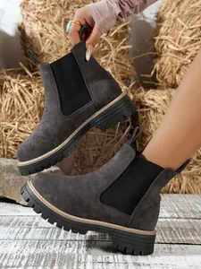 Stylish dark grey suede Chelsea boots with chunky lug sole in a rustic hay setting.