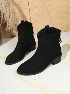 Detailweergave van zwarte suède western enkellaarsjes met spitse neus en stevige blokhak.