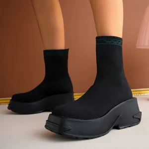 Close-up detail of black breathable knitted sock boots with thick platform wedge sole