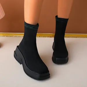 Detailed view of black breathable knit sock boots with a thick platform wedge sole
