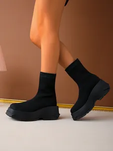 Detail of black fly-knit sock boots with chunky platform soles worn by a model