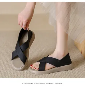 Close-up of comfortable black cross-strap sandals with thick beige flat soles in Roman style.