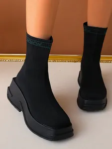 Close-up of black breathable fly-knit sock boots with thick platform sole and chunky heel