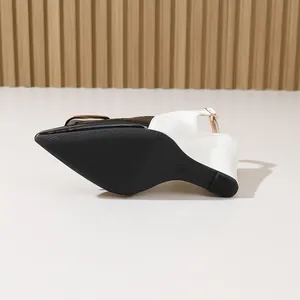 Détail de la semelle noire antidérapante et du talon compensé blanc de chaussures slingback.