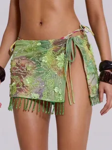 Detail of green floral sequined beach skirt featuring beaded fringe and side wrap tie.