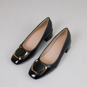 Detailopname van zwarte pumps met krokodillentextuur en een gouden appelgesp detail