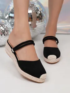Detail van zwarte suède espadrilles met sleehak, gevlochten jute zool en dubbele bandjes.