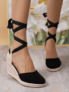 Sandalias de cuña con cordones y elegante suela de yute alpargata en pies de modelo