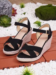 Detaillierte Nahaufnahme schwarzer Keilsandalen mit gekreuzten Riemen und Jute-Plateau