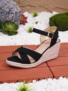 Detailaufnahme schwarzer Keilsandalen mit Kreuzriemen und geflochtener Jutepsohle