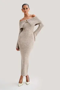 Detailed close-up of an elegant off-the-shoulder knitted maxi dress with a gold metal clasp.