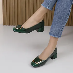 Detailweergave van donkergroene pumps met lage hak en krokodillenpatroon in reliëf