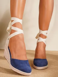 Primer plano de sandalias de cuña azul marino con cintas blancas para atar al tobillo