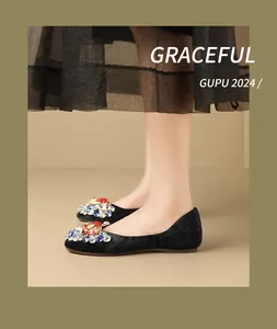 Detail of black velvet flat shoes with colorful crystal embellishments on the feet.