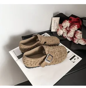 Sabots en daim marron avec boucle et clous sur magazine élégant