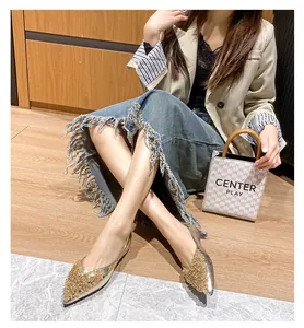 Detailansicht eleganter goldener Pailletten-Flachschuhe mit spitzer Zehenpartie.