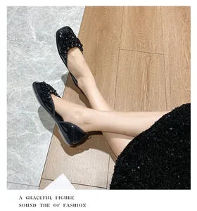 Eleganti sandali piatti neri con strass indossati con un abito di paillettes chic