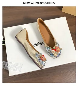 Detailansicht goldener Ballerinas im französischen Stil mit bunten Strasssteinen.