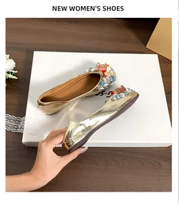 Detail von metallisch goldfarbenen flachen Schuhen mit bunten Strass- und Perlenverzierungen.