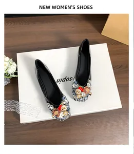 Draufsicht auf schwarze Lack-Ballerinas mit bunten Strassverzierungen auf weißer Box