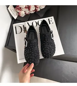 Vue détaillée de mules élégantes en daim noir cloutées avec boucle et doublure en peluche.