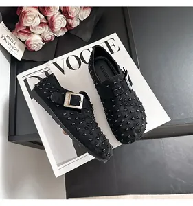 Vue détaillée de mocassins noirs cloutés avec boucle argentée sur magazine de mode