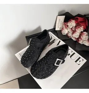 Vue rapprochée des sabots noirs cloutés en faux daim avec une boucle en argent