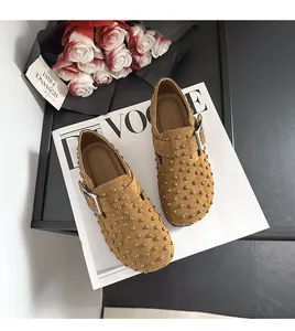 Vue de dessus de sabots en daim camel à clous sur fond de magazine blanc élégant
