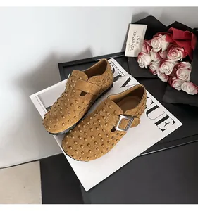 Gros plan de mocassins en daim marron avec clous métalliques et boucle réglable
