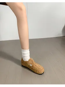 Détail de sabots en daim marron cloutés portés avec des chaussettes blanches