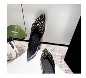 Detailansicht schwarzer spitzer Ballerinas mit luxuriöser Perlenverzierung.