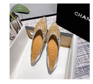Detailansicht silberner spitzer Ballerinas mit schimmerndem Goldkristall-Zehendekor