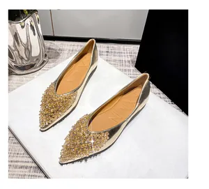 Nahaufnahme von goldenen spitzen Flats mit luxuriösen Kristall- und Paillettenverzierungen.