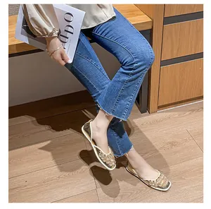 Vista dettagliata di eleganti ballerine d'Orsay dorate con strass indossate con jeans blu.