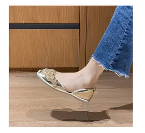 Dettaglio ravvicinato di scarpe basse d'Orsay oro con strass indossate con jeans