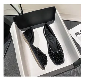 Vista dettagliata di eleganti scarpe basse nere con strass in una scatola minimalista