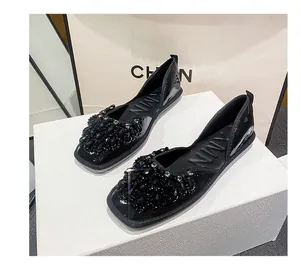Eleganti ballerine nere con decorazioni in strass su una scatola bianca per esposizione