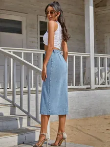 Back view detail of a high-waisted light blue denim midi skirt on a model by a beach