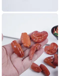 Close-up detail of realistic miniature braised meat food models held in a hand for scale
