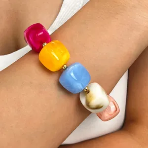 Nahaufnahme eines bunten Bohemian-Perlenarmbands mit großen Harzwürfeln und Goldzwischenstücken